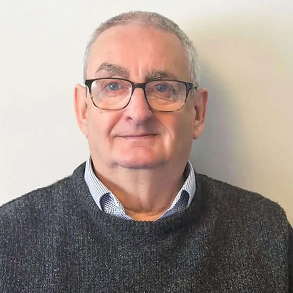 headshot of man wearing glasses and a grey jumper.