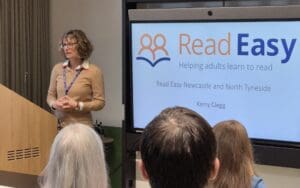 Close up shot of woman presenting. The presentation screen says 'read easy'