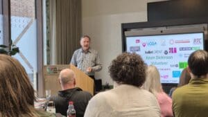 Close up shot of man presenting. He is wearing a grey shirt